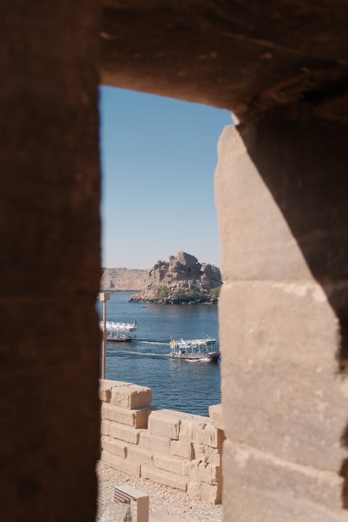 View through ancient Egyptian temple ruins toward the Nile River, framed by carved stone columns