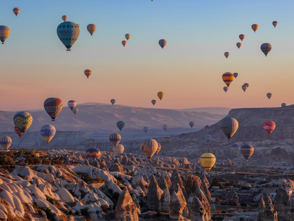 Dozens of colorful hot air balloons drifting over Cappadocia's volcanic landscape at sunrise, Turkey