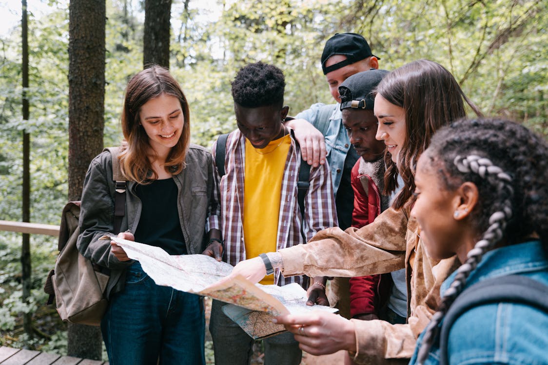 Diverse group of young adults studying a map together outdoors on a clear day