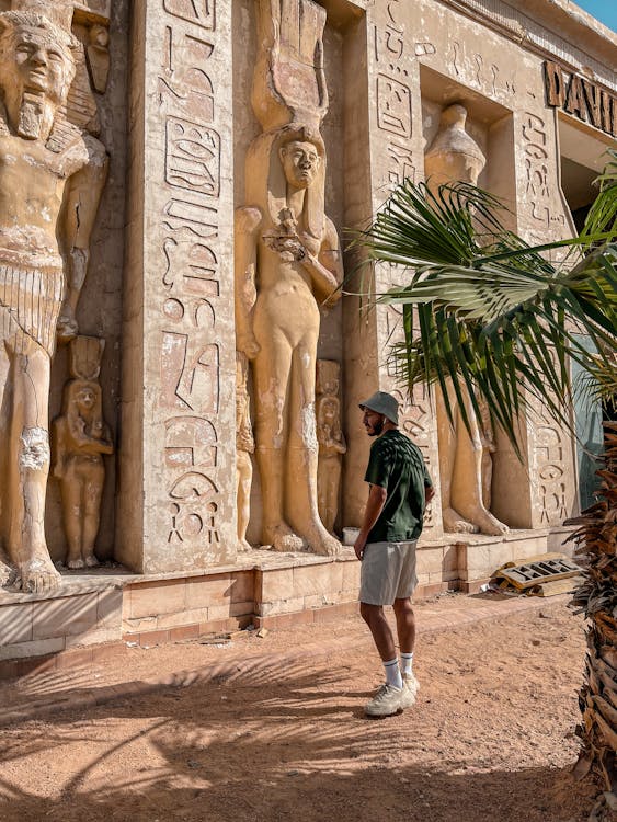 Tourist guide standing beside ancient Egyptian wall carvings at a Luxor temple complex