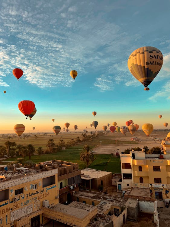 Colourful hot air balloons drifting over Luxor's ruins and farmland at sunrise
