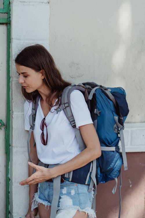 Young woman solo traveler with backpack exploring outdoors, ready for adventure on her own terms
