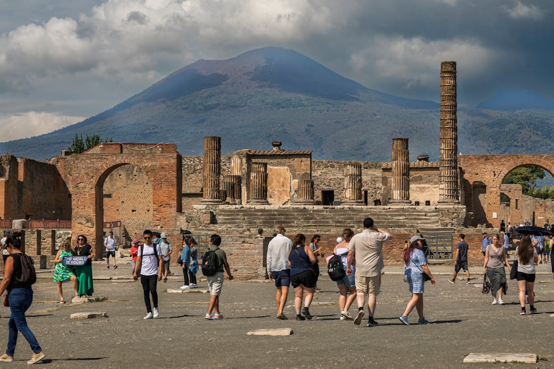 Tourists walking through ancient ruins at Pompeii on a sunny guided tour day