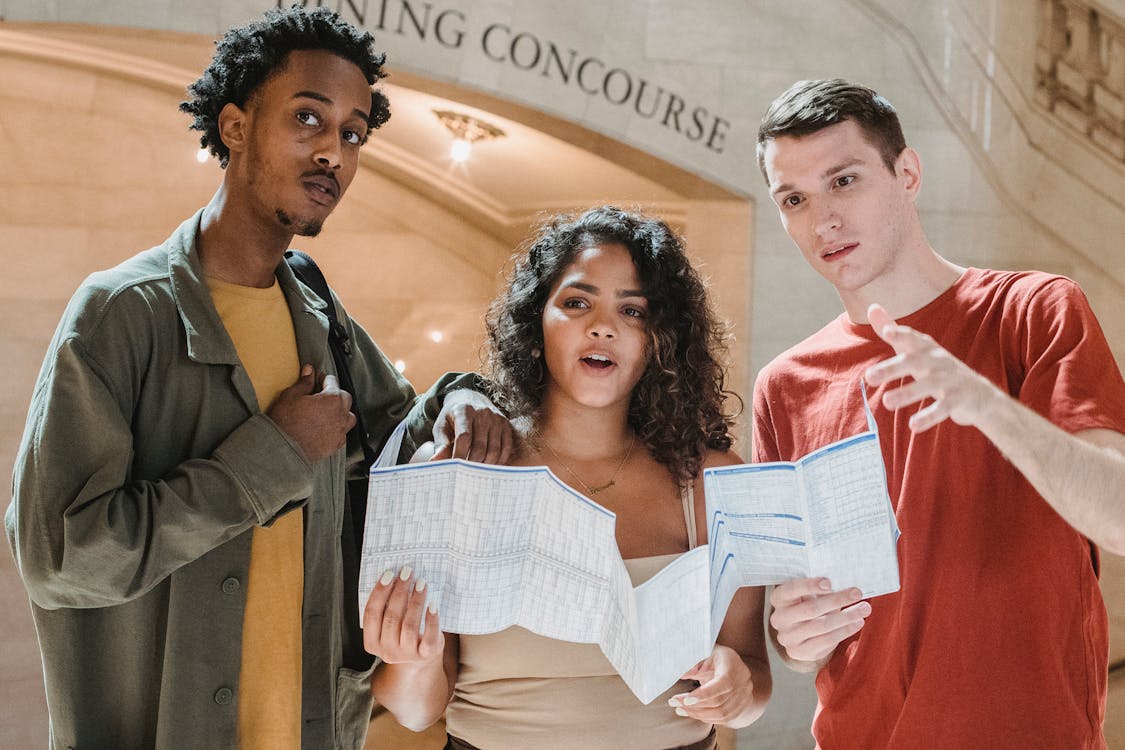 A diverse group of travelers using a map together indoors, working through a decision about where to go