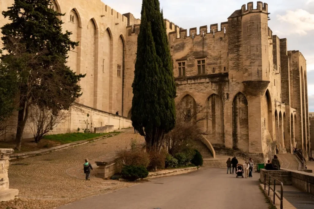 The Palace of the Popes illuminated by evening light against the backdrop of Avignon and the Rhone River