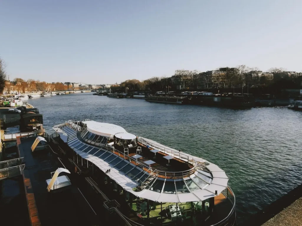 Best Seine River Cruises for First-Timers (2026) ToursZoom <alt for query 0>: A picturesque view from the deck of a Seine river cruise ship in Paris during sunrise.