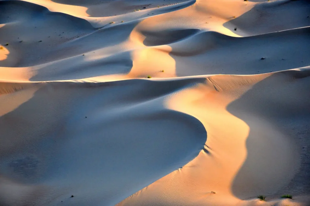 Aerial view of golden dunes with no vehicles, capturing the serene beauty of Dubai's desert