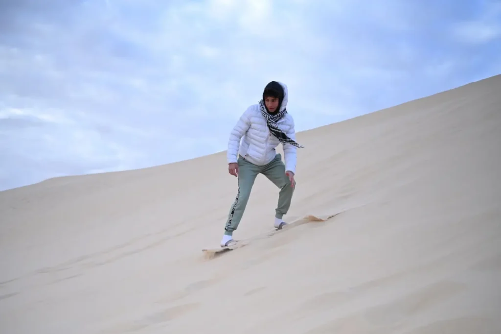 Sandboarding on Dubai desert dunes illuminated by morning light