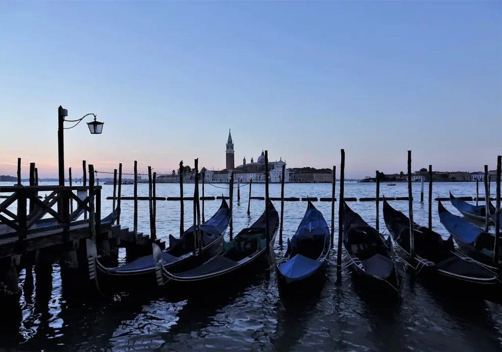 Italy tours in September: Harvest season, warm coast, and cultural touring ToursZoom Gondola ride through Venice at dusk, reflecting the city's lights on the water