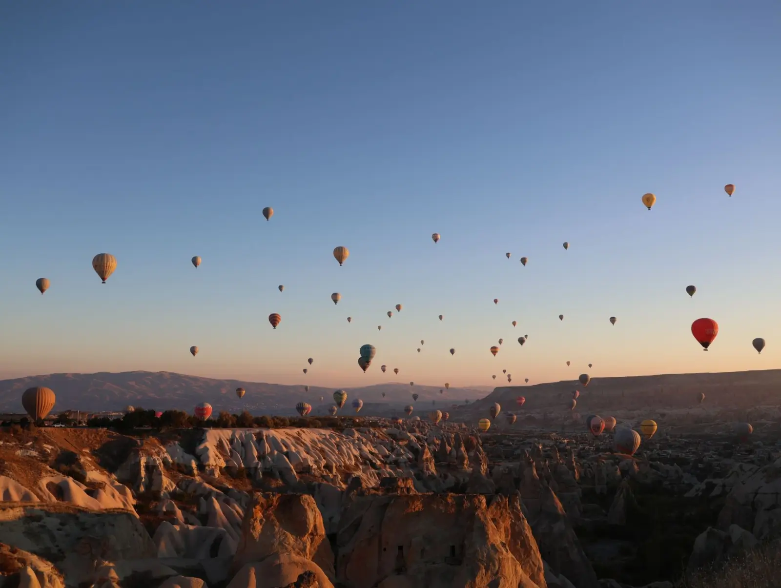 Turkey tours in April: Spring culture routes and Cappadocia comfort ToursZoom Hot air balloons rising over the fairy chimneys of Cappadocia at dawn